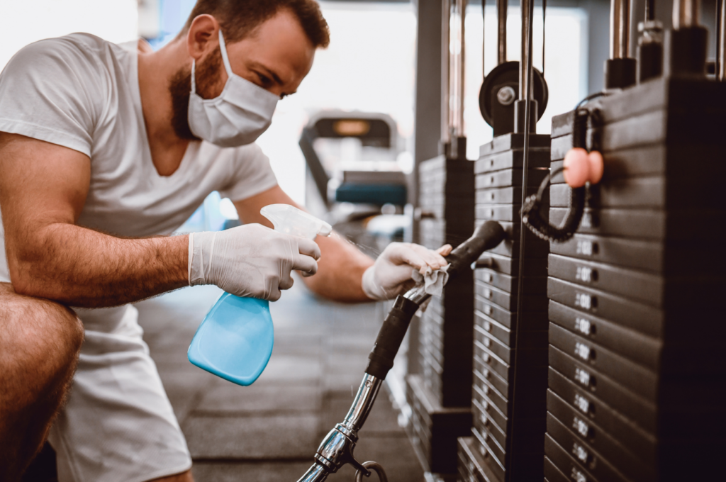 aluno higienizando aparelho na academia na pandemia